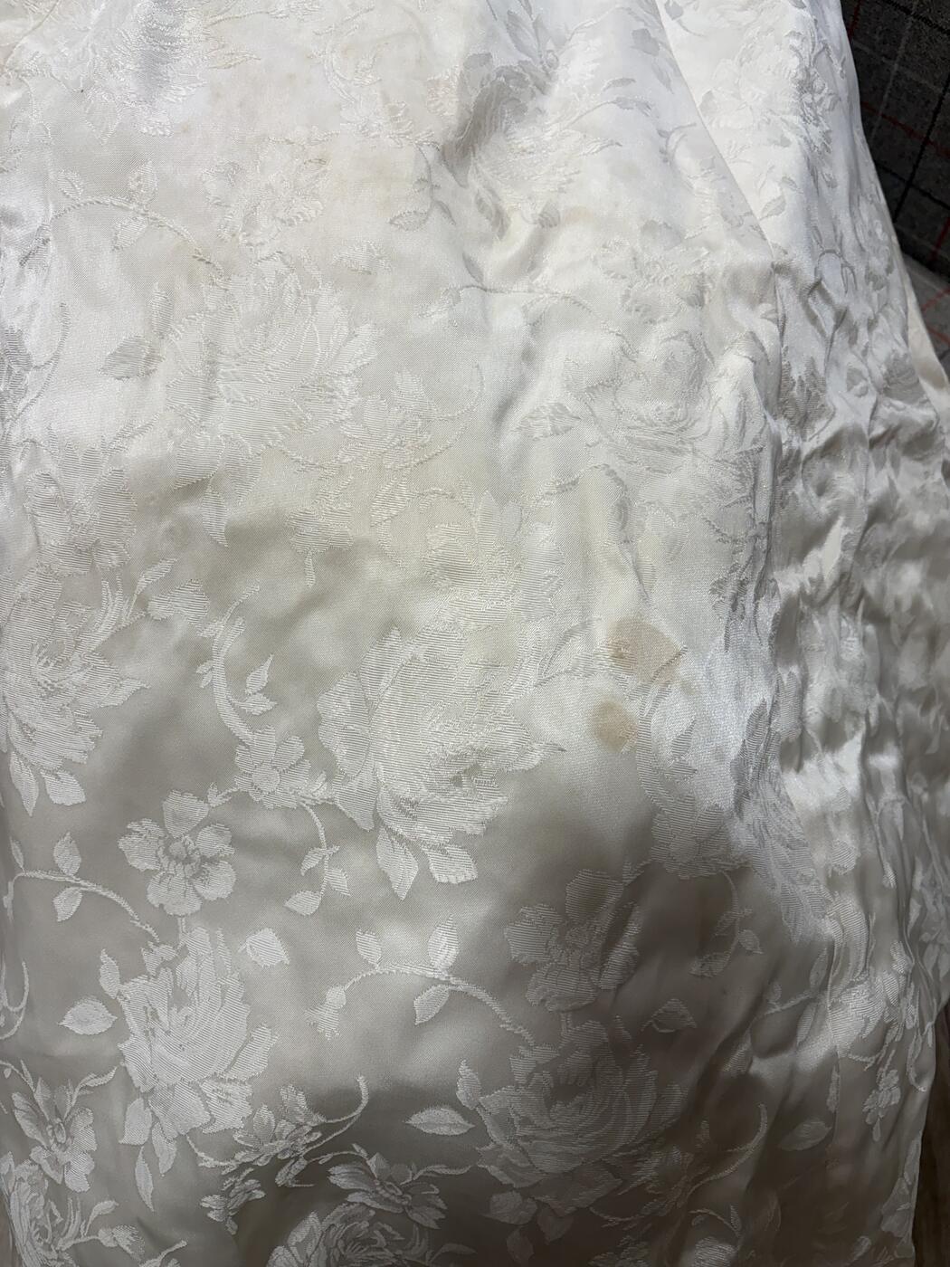 Brown age spots on the satin jacquard skirt of an antique wedding dress
