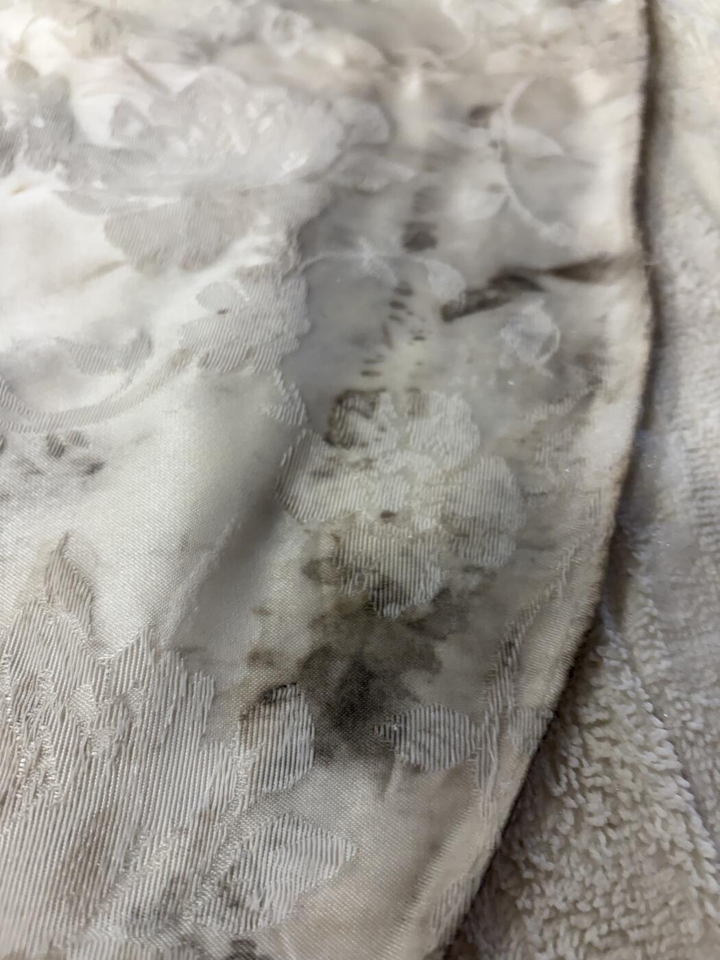 Antique jacquard wedding dress hem with heavy grey soiling before cleaning